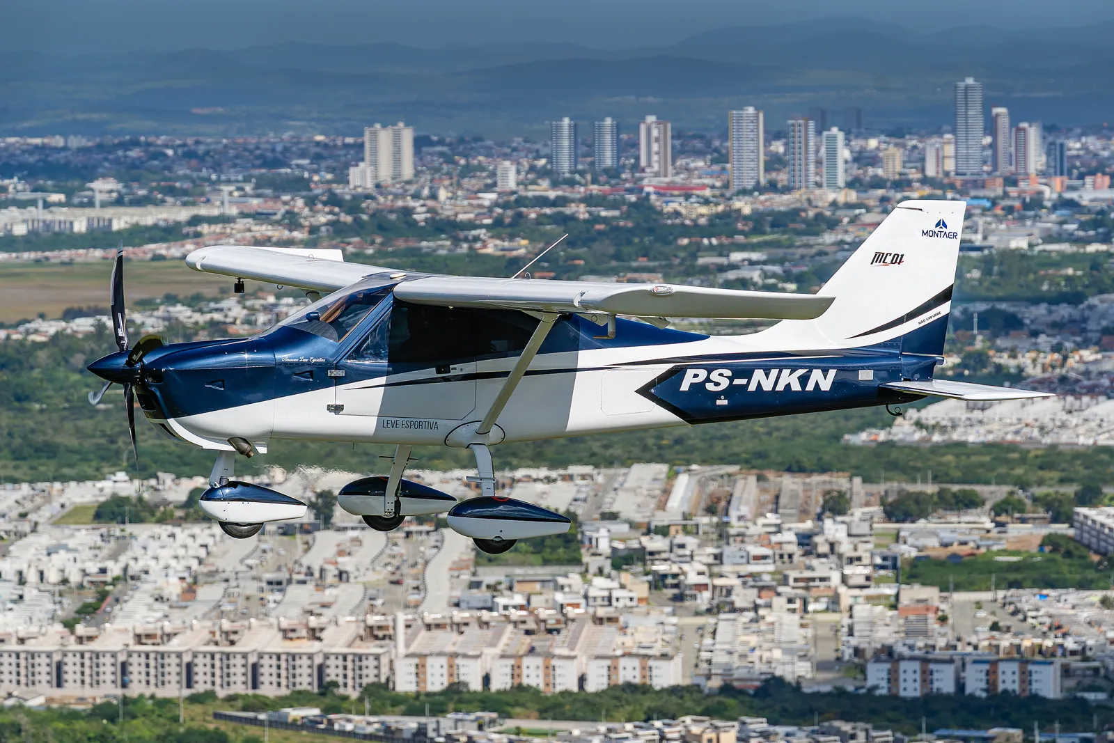 MC01 Fast em voo com prédios de uma cidade ao fundo